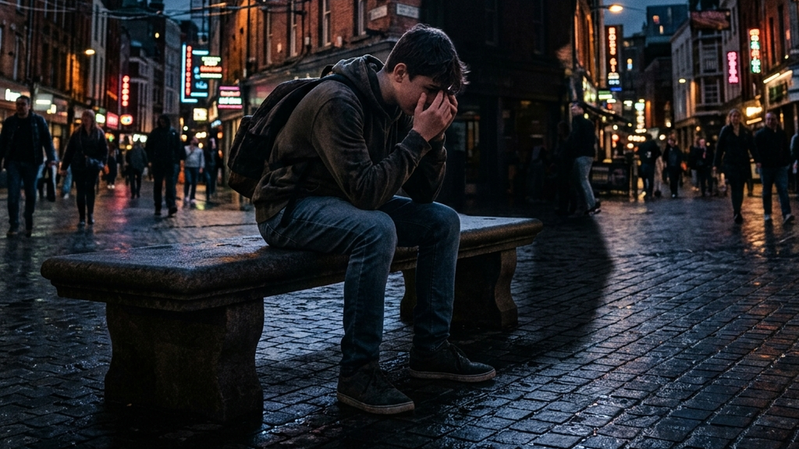 A teenager sitting alone on a wet street bench at night, head in hands, under the glow of a billboard — an image about moral panic over social media